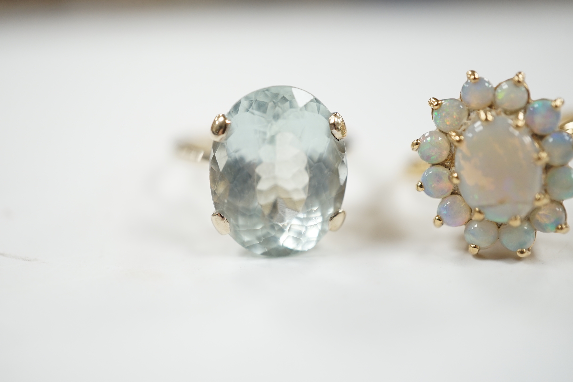 A 14k yellow metal and white opal set oval cluster ring, size P/Q, gross weight 4.1 grams and a gilt white metal? and oval fancy cut aquamarine set ring.